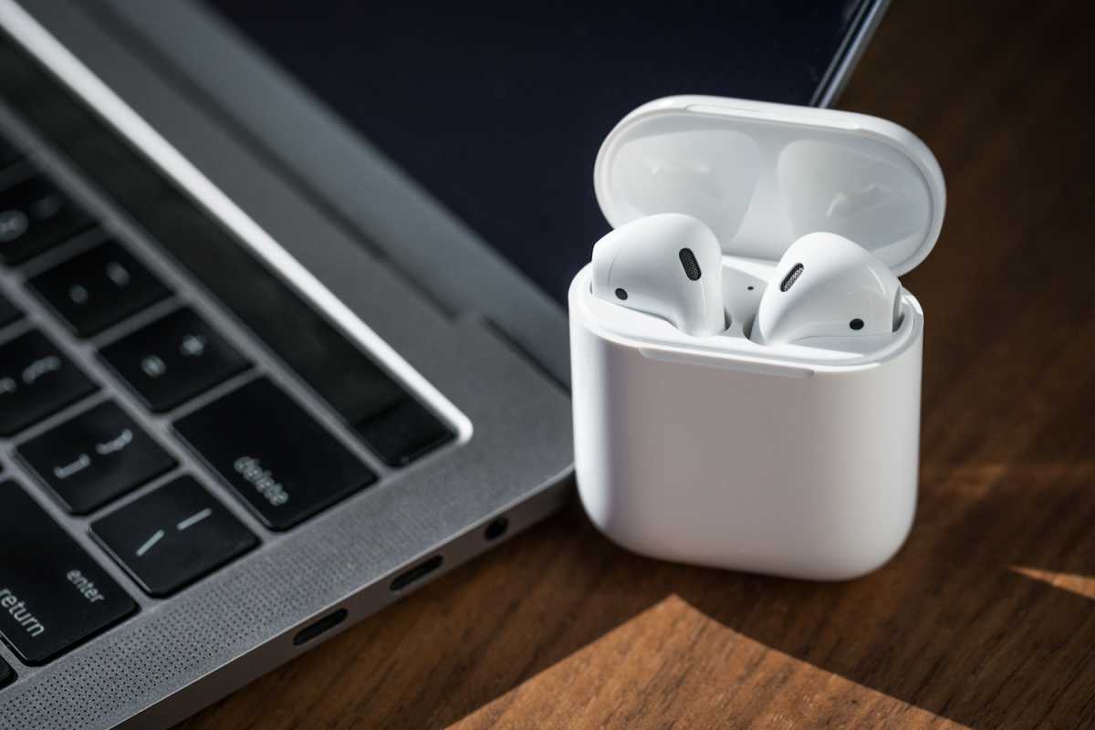 Airpods case open next to a MacBook
