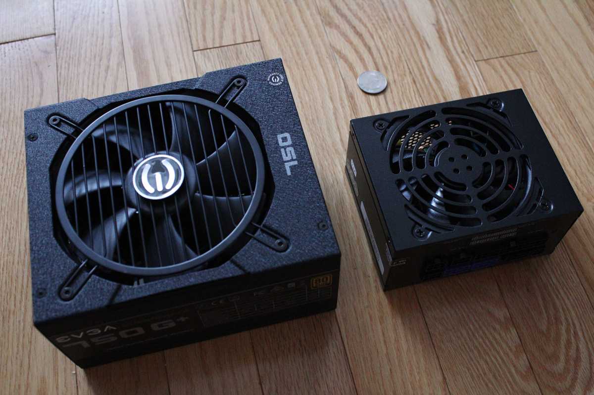 ATX PSU next to SFX PSU with a quarter nearby for scale, all on a wood floor