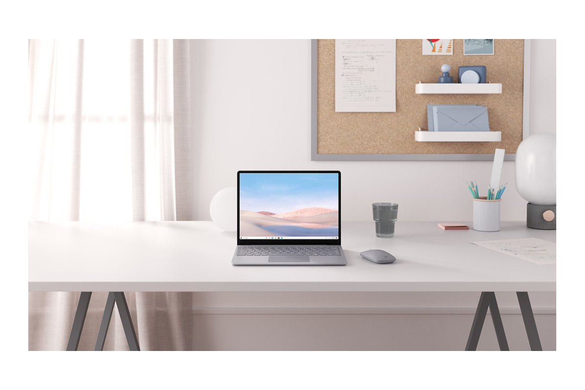 The Surface Go on a white desk with various other desk items in the background