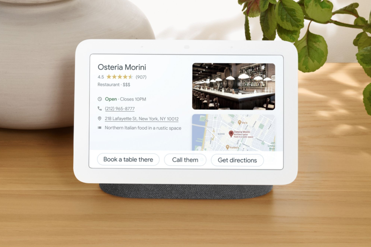 The Google Nest Hub smart display displaying Google Map info on a light wood desk.