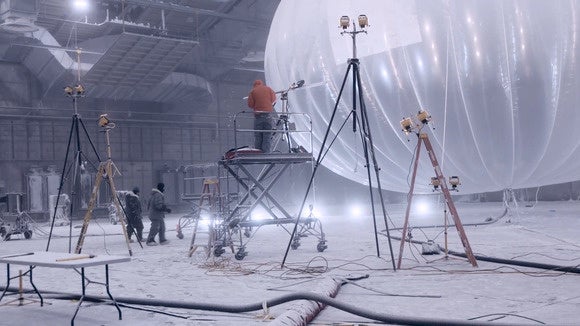Three people working on a giant transparent balloon in sub-zero temperatures.
