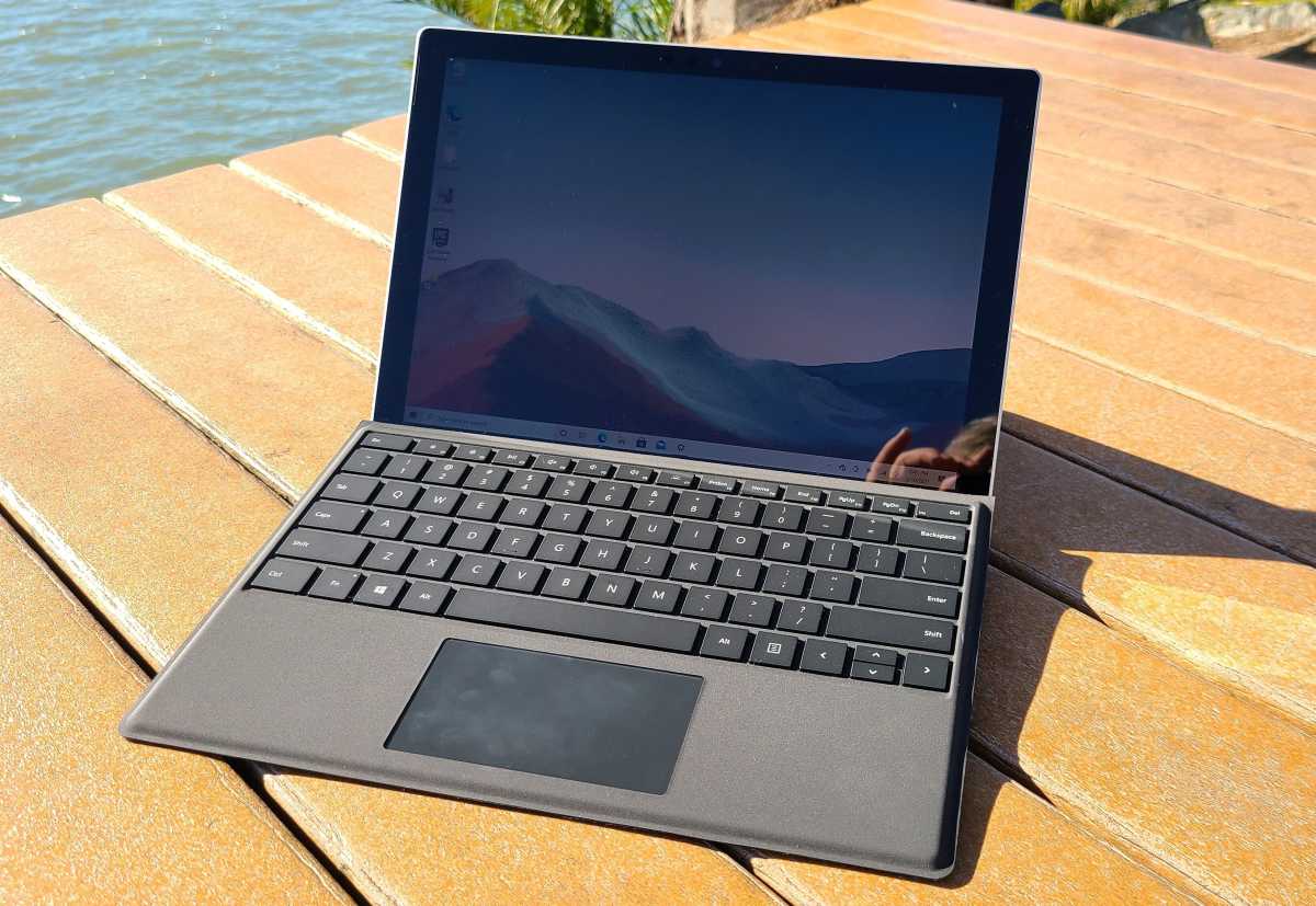 The Surface Pro 7+ on a deck near some water in sunlight.
