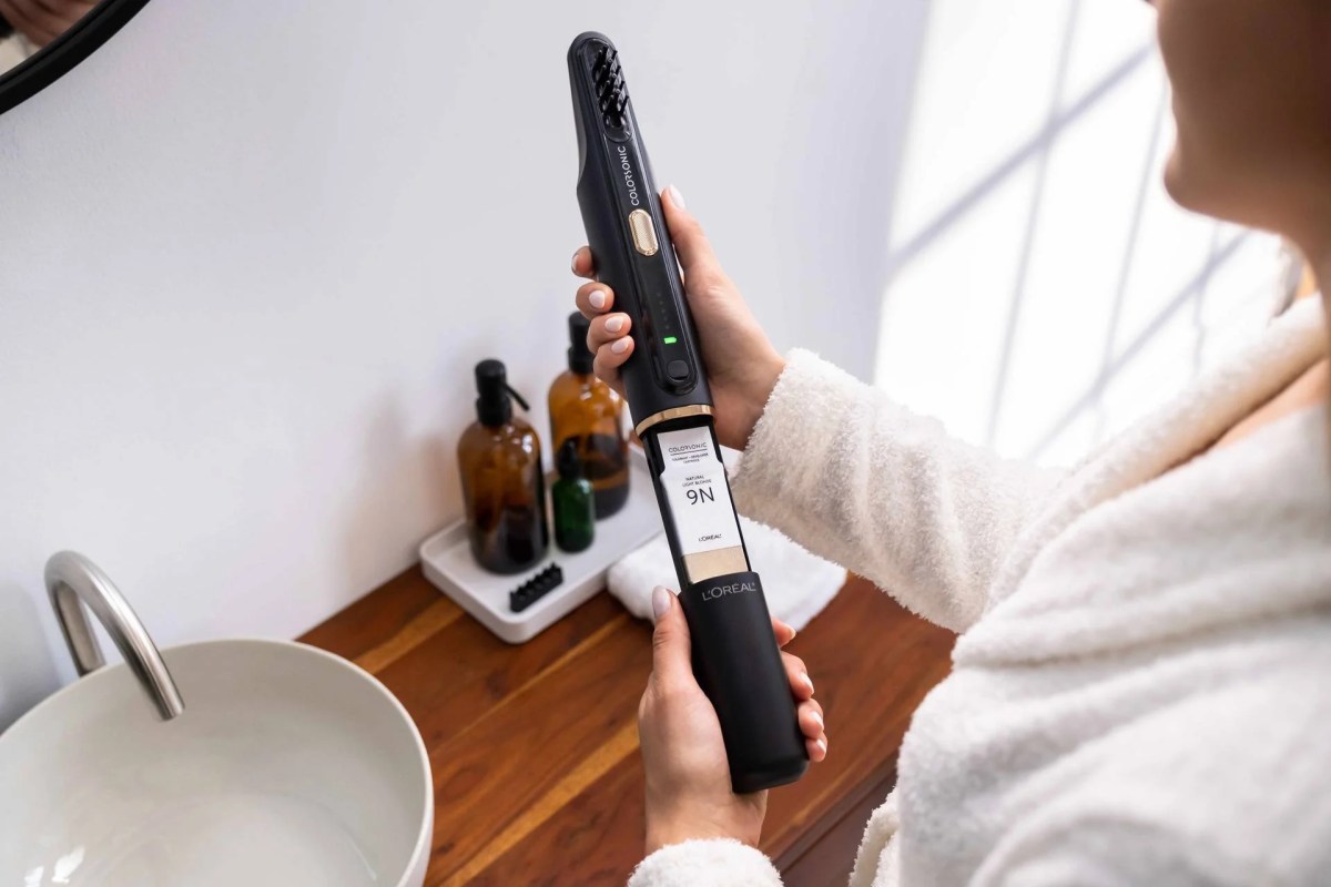 Person Holding L'Oreal Colorsonic Wand Over A Sink