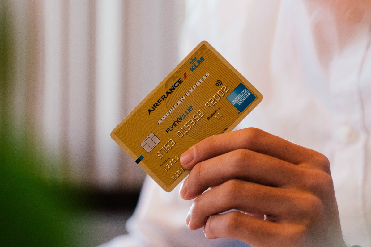 Person holding a gold-colored American Express credit card in their hand