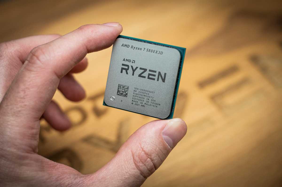 A hand holding a Ryzen 7 5800X3D processor