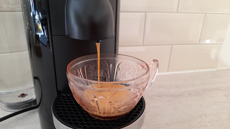 The Vertuo Plus is dispensing a stream of coffee into a cup 