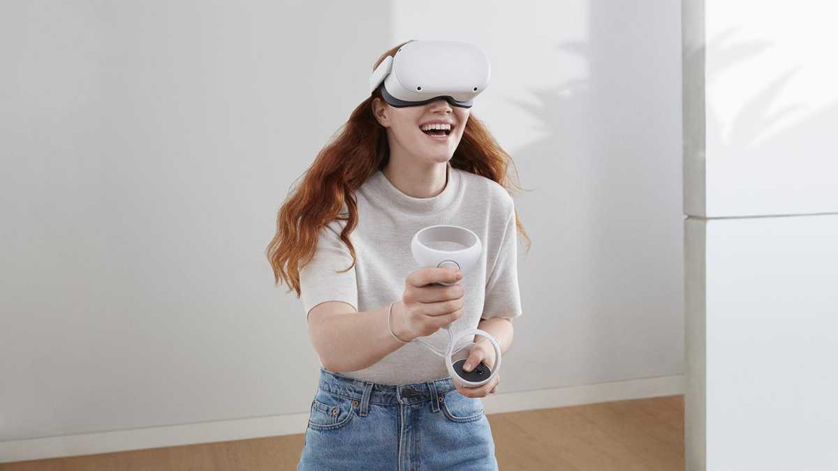 A woman using the Oculus Quest 2, smiling in a plain room