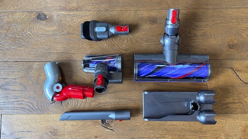 Dyson V12 Absolute's accessories, including spare cleaning heads and a wall dock