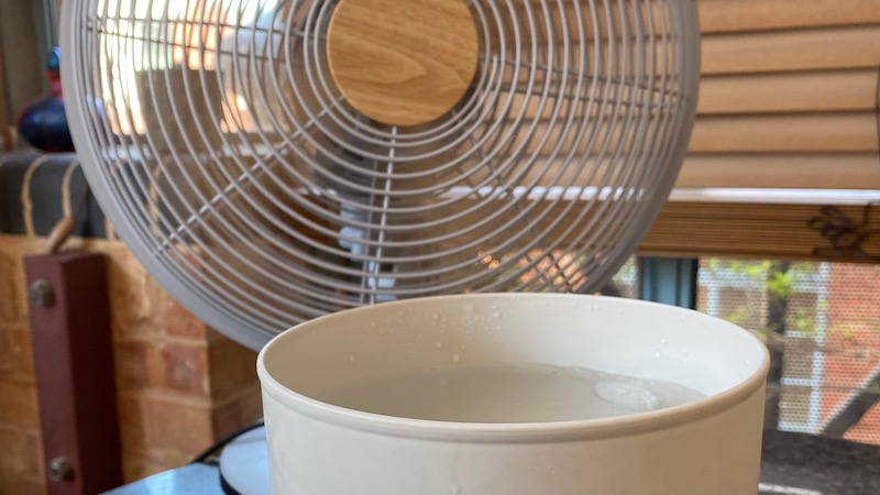 A block of ice in a bowl in front of a fan