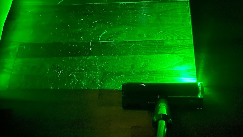 The V12's green laser illuminating dust and hair