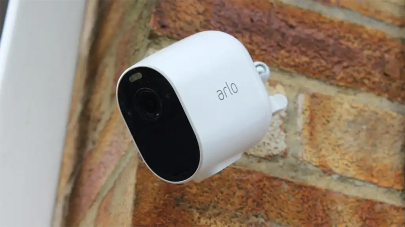 An Arlo home security camera mounted to a brick wall