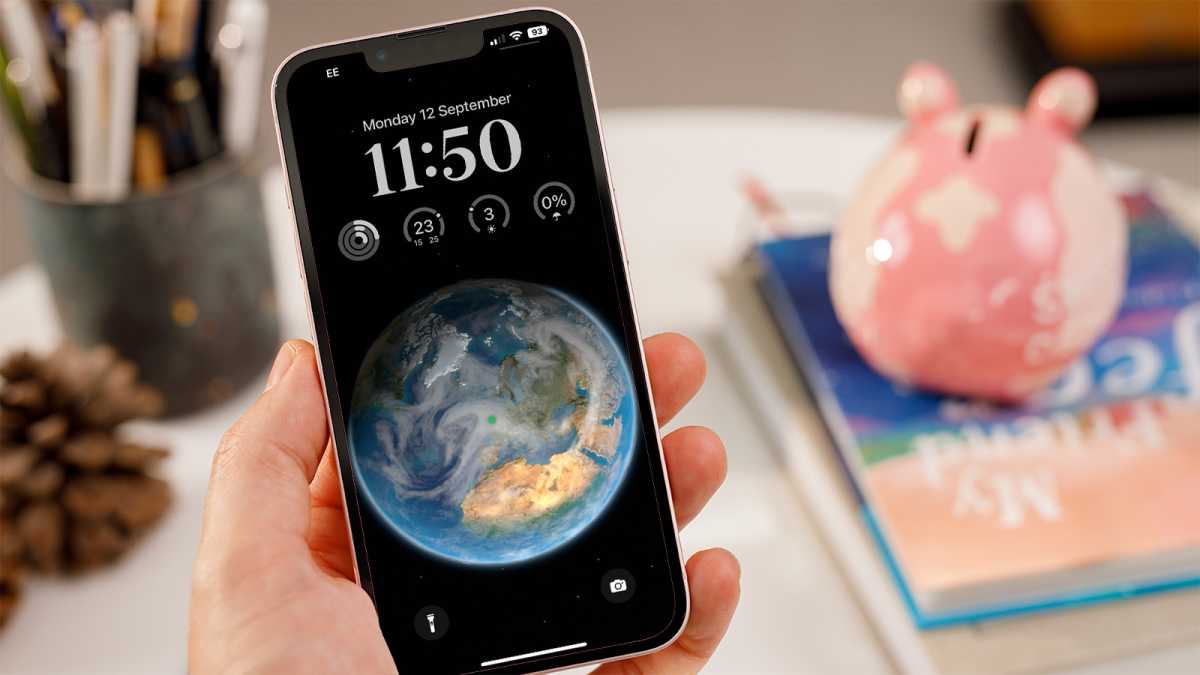 iPhone в ръка с новото оформление на заключен екран