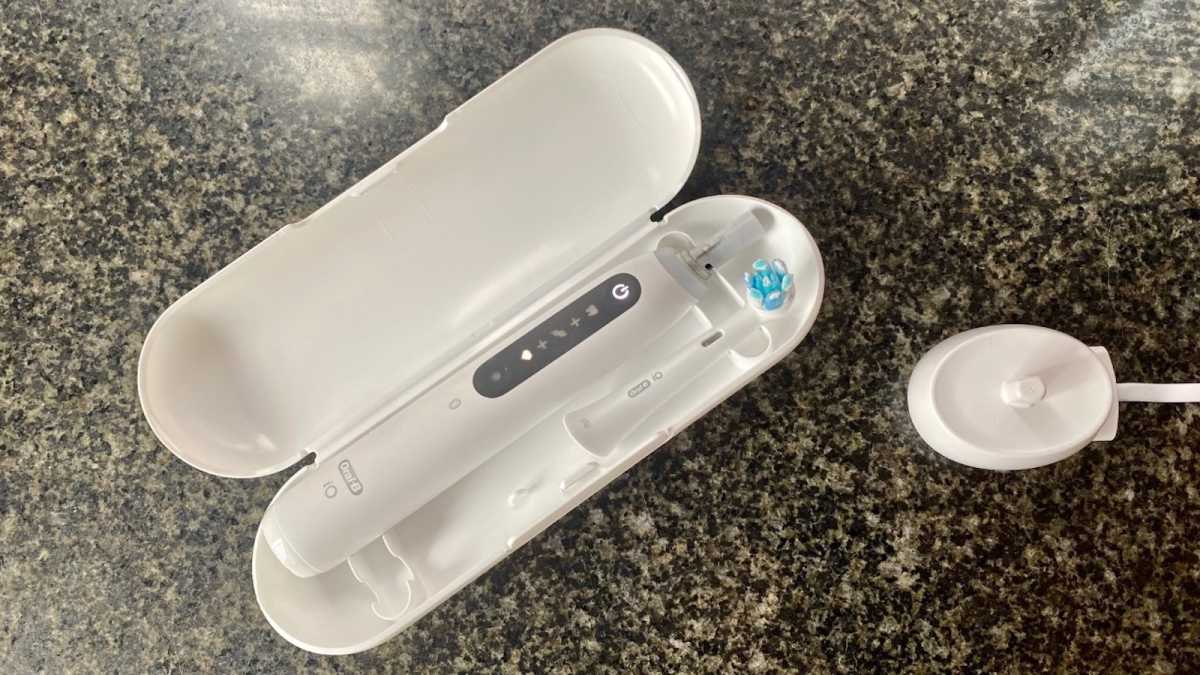 Oral-B iO5 in a white travel case, with a charging stand nearby