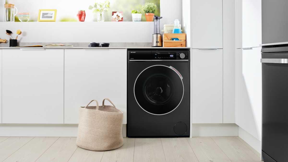 Black washer dryer with a laundry basket in front of it 