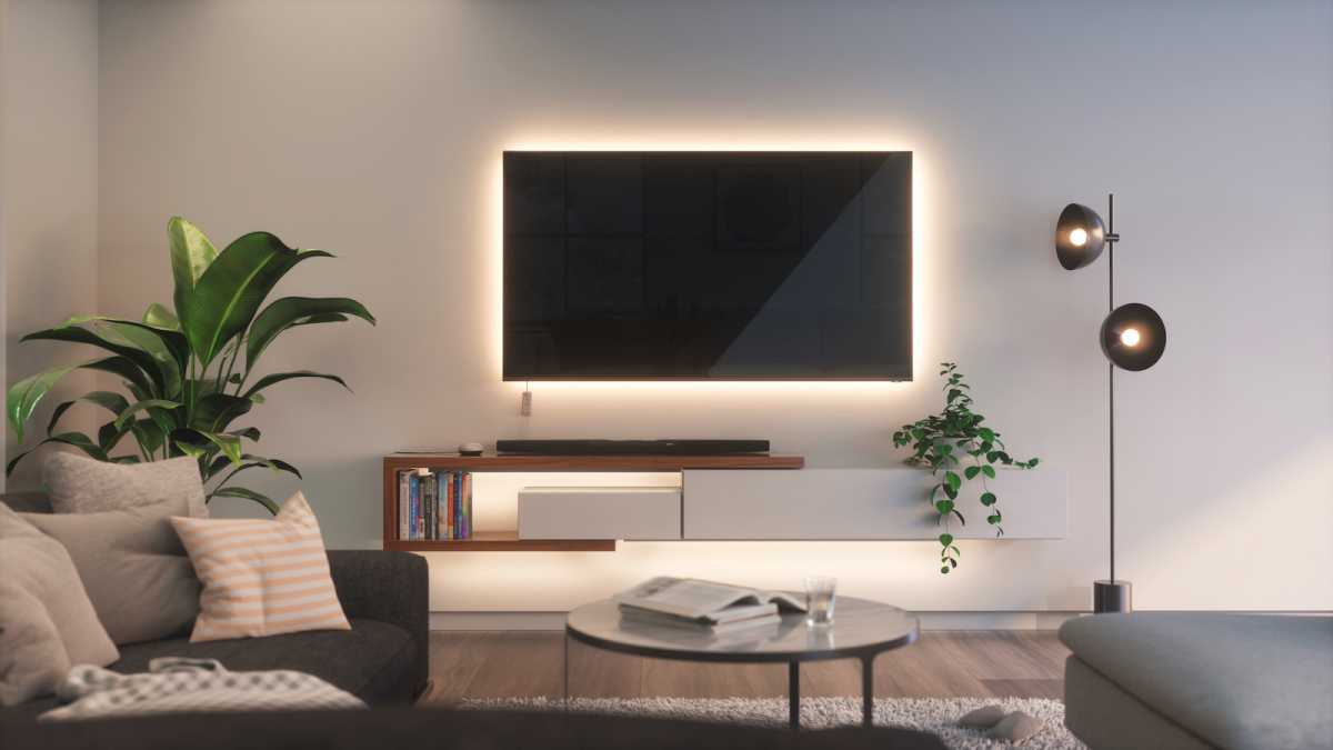 A living room with a TV backlit by a light strip and white bulbs in a lamp
