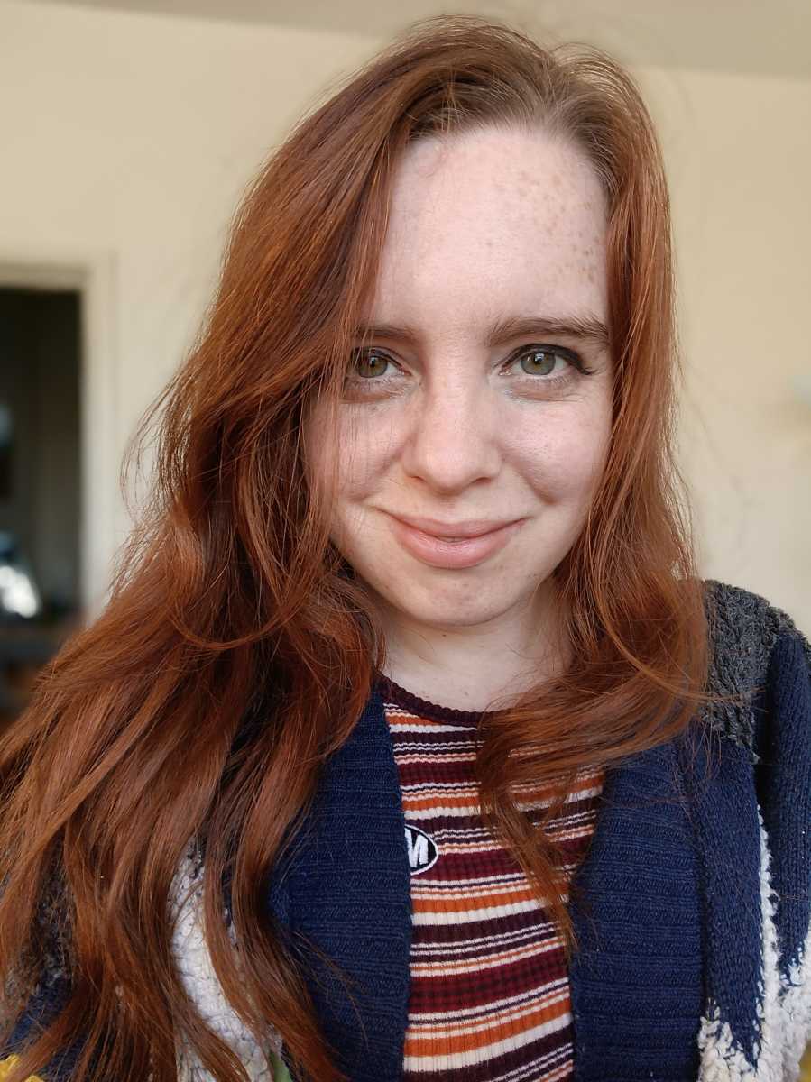 Selfie of red-haired woman with blue cardigan and striped shirt