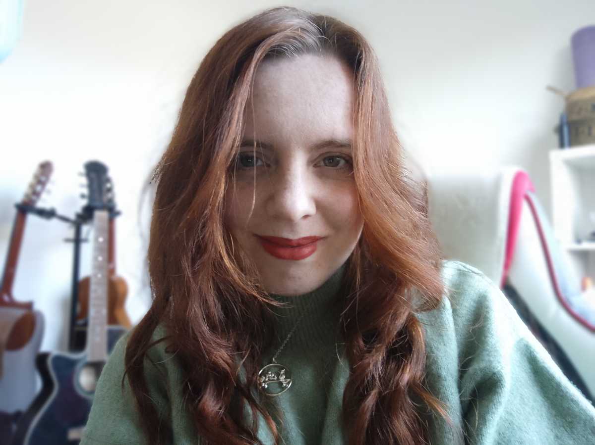 Selfie of red-haired woman in green jumper, indoors