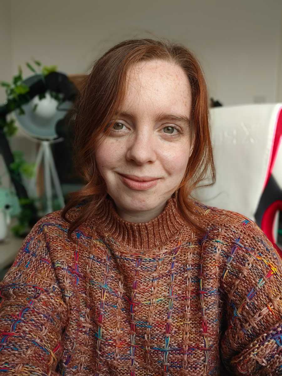 Selfie of woman in orange jumper indoors on portrait mode