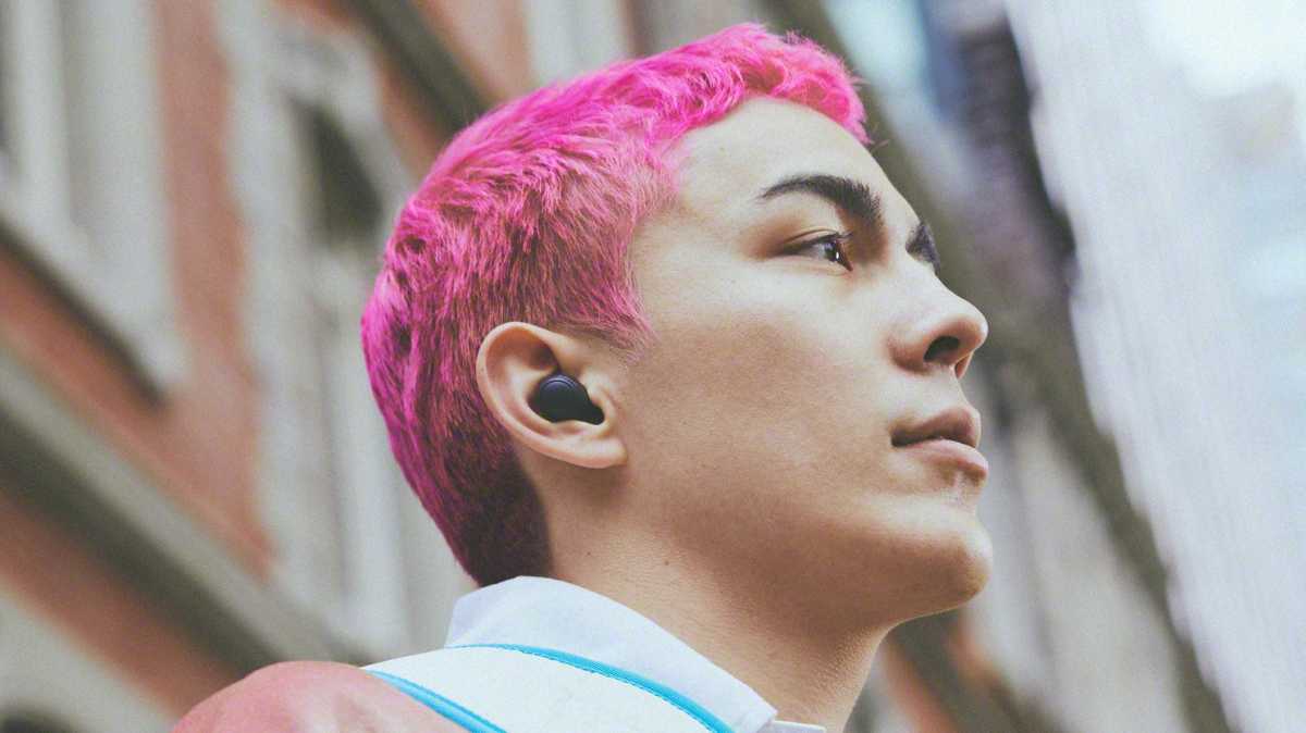 Person with pink hair wearing Sony Wf-C700N wireless earbuds