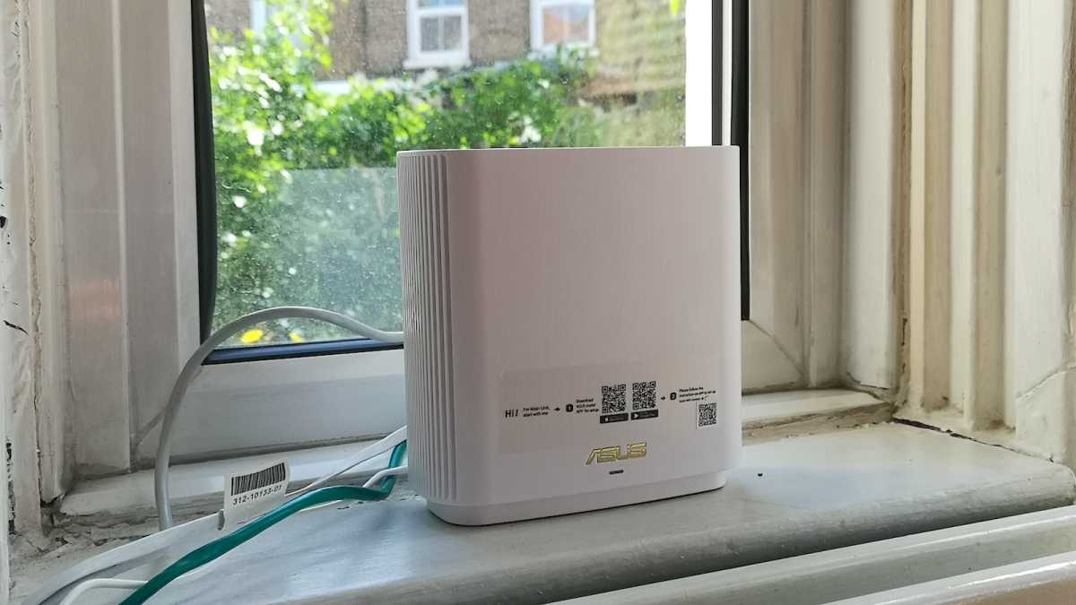 En hvid Asus ZenWiFi XT9 mesh Wi-Fi-enhed tilsluttet et modem