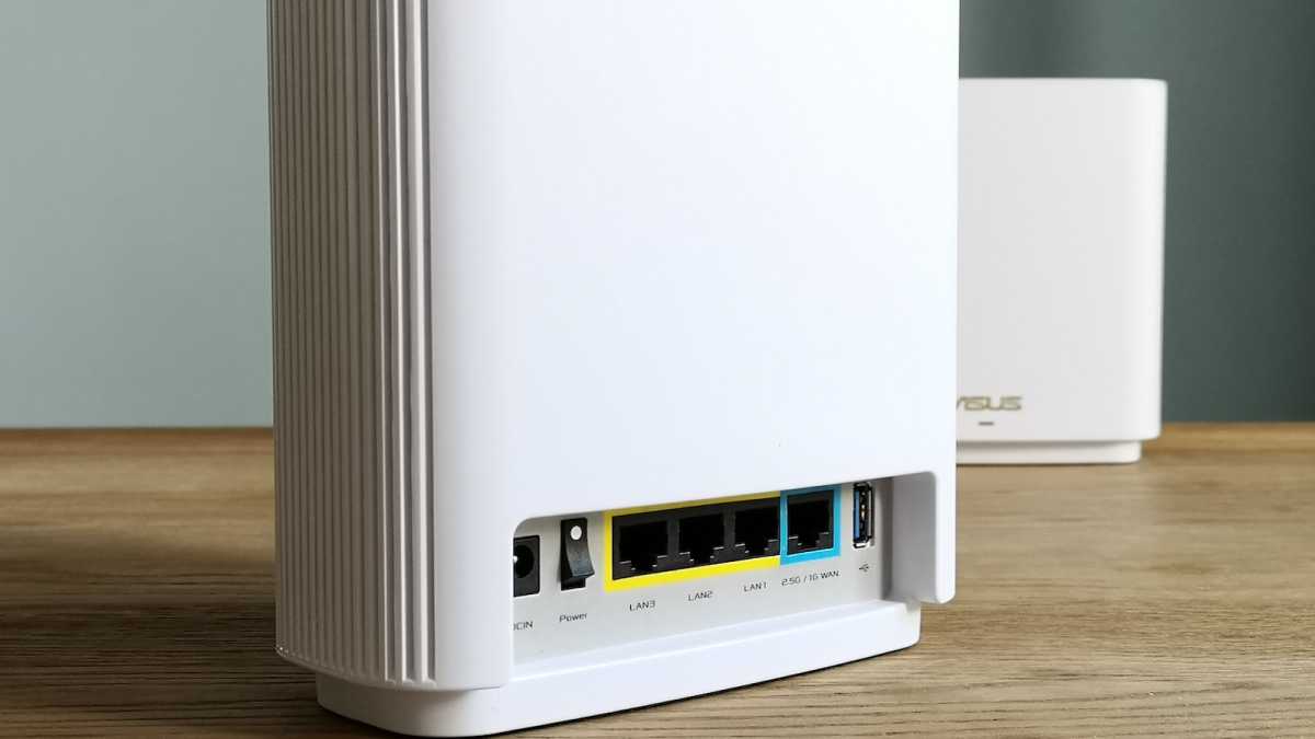 A close-up view of a white Asus ZenWiFi XT9's ports: three Ethernet LAN ports, one Ethernet WAN port, and a USB port