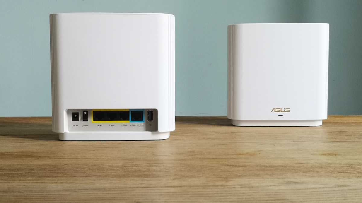 Two white Asus ZenWiFi XT9 units, one facing away, showing off the three Ethernet LAN ports, the WAN port, and the USB port