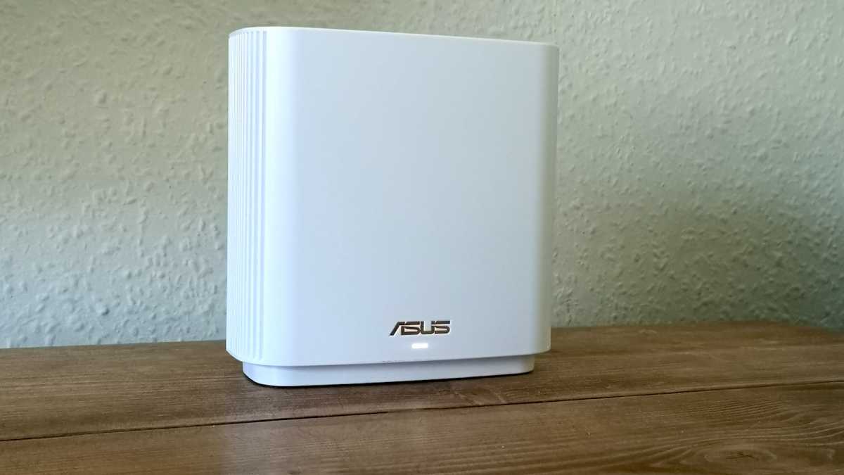 A white Asus ZenWiFi XT9 router powered on and connected via Wi-Fi to the primary node. The status LED is flashing white, indicating that it's connected to the Internet