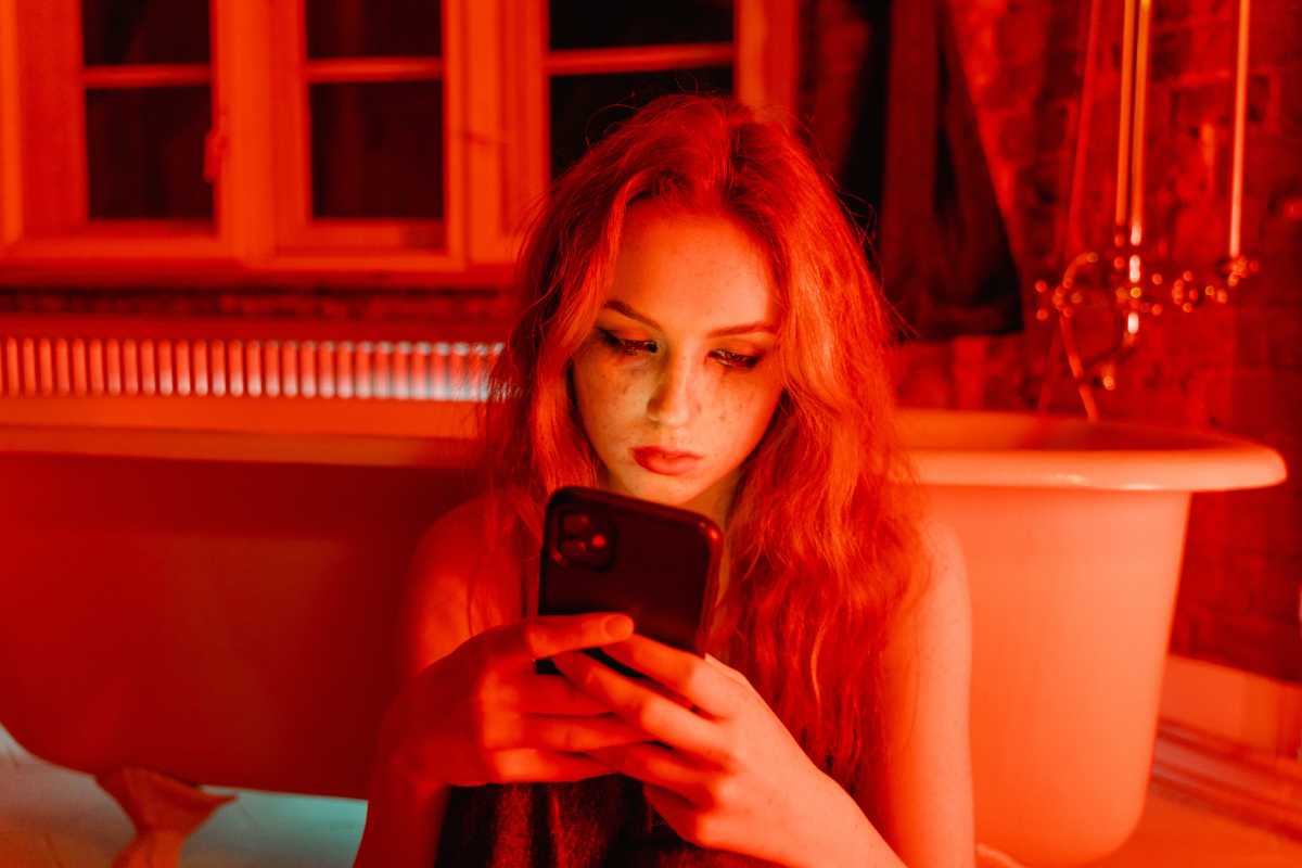 Weinende Frau mit Handy im Badezimmer