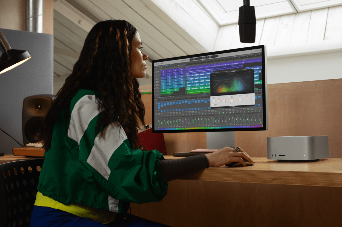 Kvinna vid arbetsstation med skärm och Mac Studio. Hon arbetar med ett ljudprojekt.