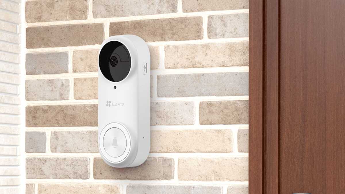 EZVIZ video doorbell in white, beside a front door