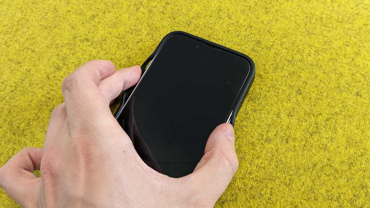 Die Seiten einer Silikonhülle fürs iPhone 14 werden mit zwei Fingern aufgespreizt