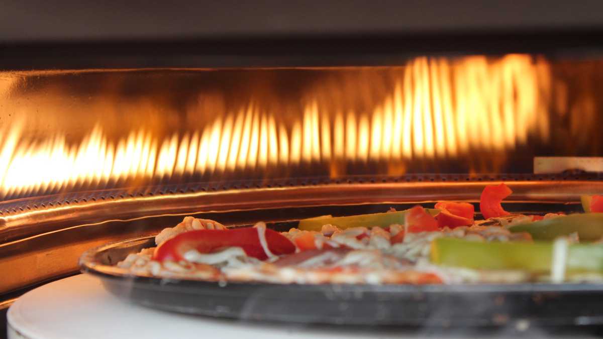 Cooking flames and pizza inside the pizza oven
