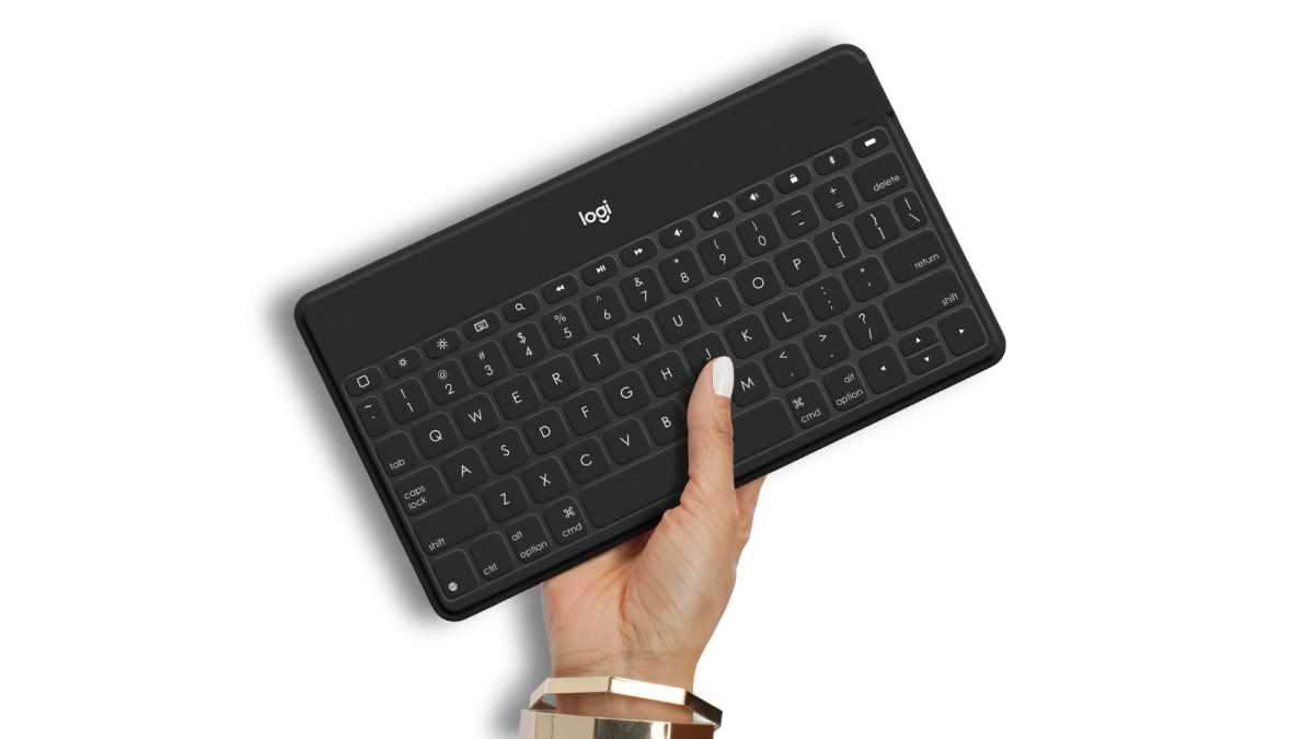 Eine Frauenhand hält eine schwarze Logitech Keys-to-Go-Tastatur mit QWERTY-Layout
