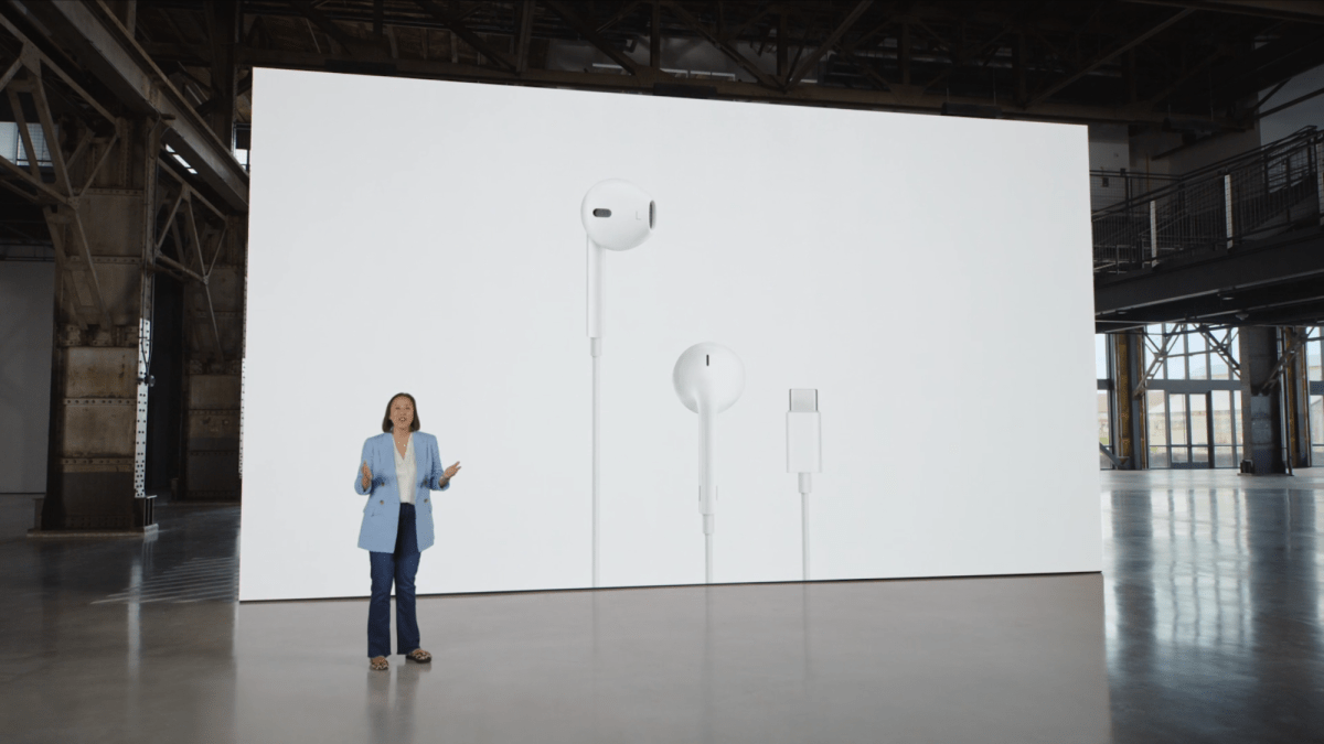 Frau hält Präsentation vor einer riesigen Leinwand mit kabelgebundenen Apple Earpods mit USB-C-Anschluss