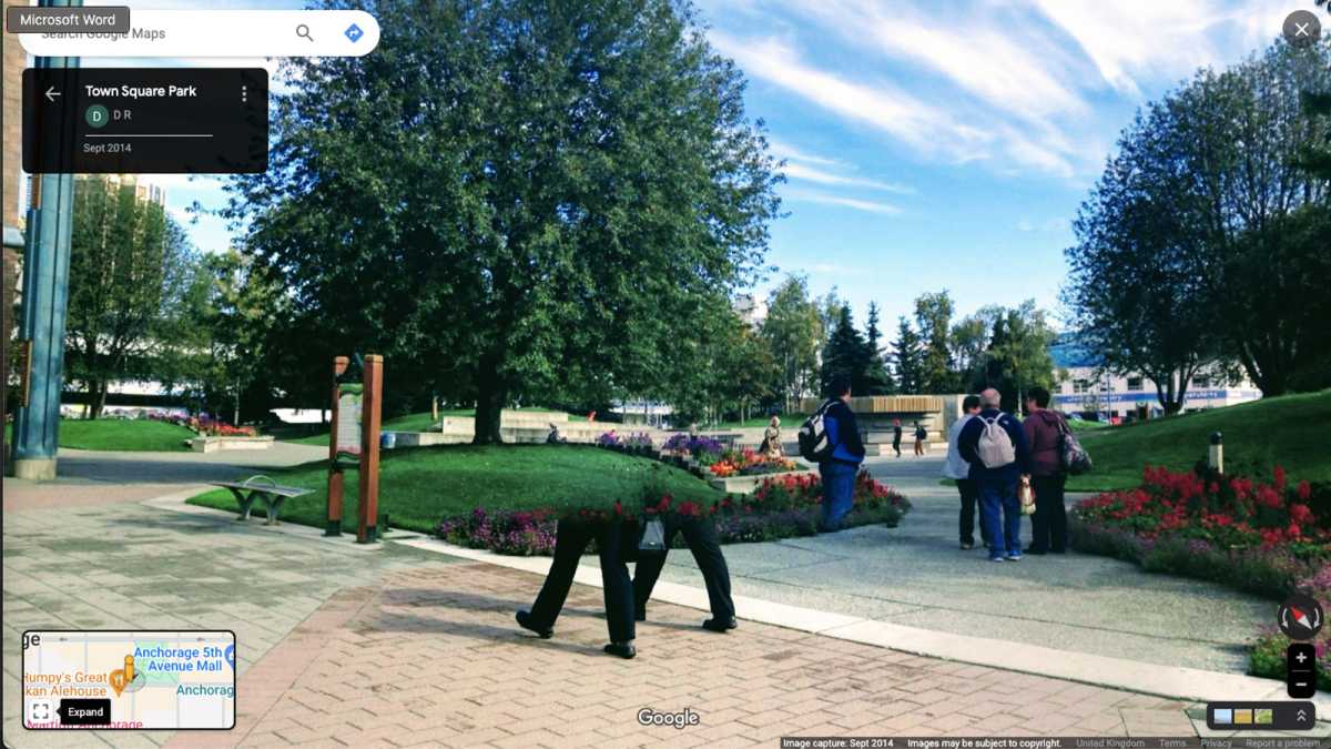 Two pairs of legs walk through a park in a Google Street View image