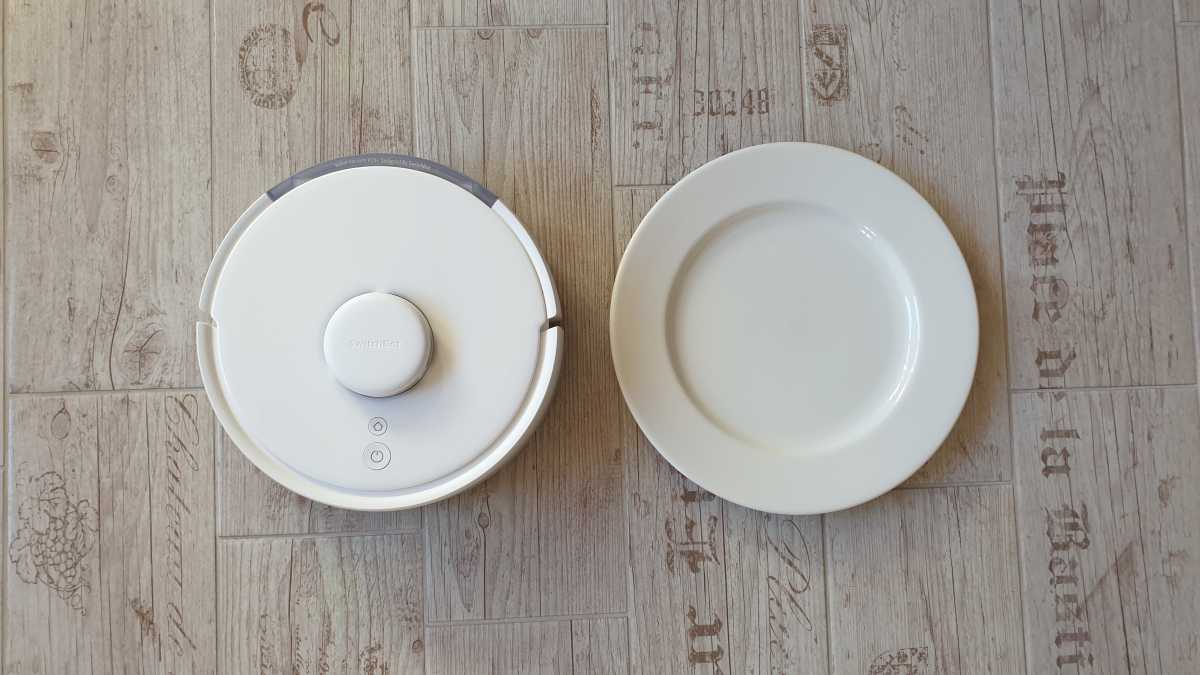 A view of the Switchbot K10+ robot vacuum and mop beside a white dinner plate.