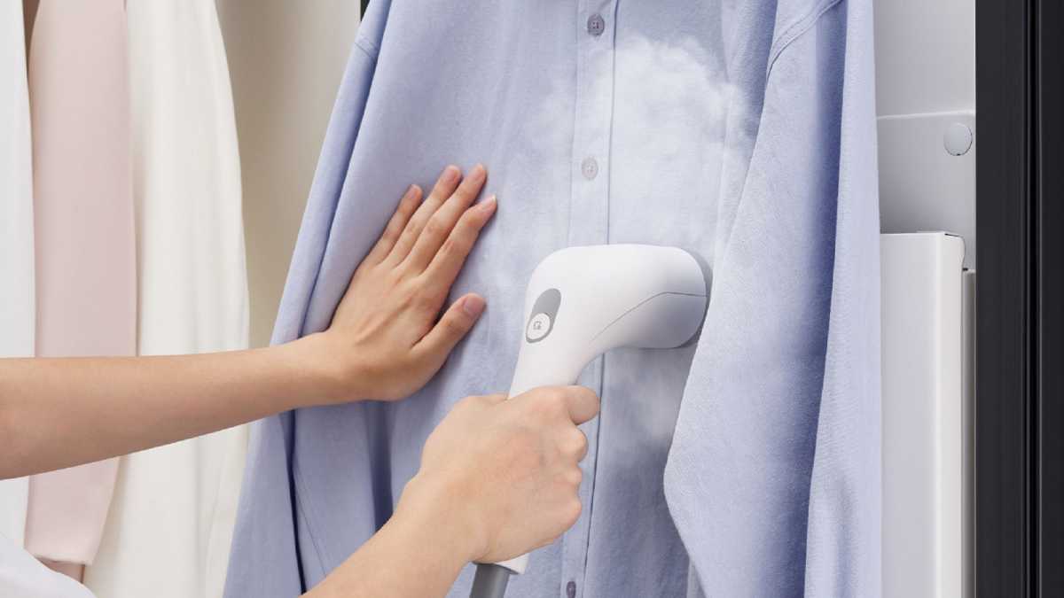 A woman using the portable steamer on a shirt