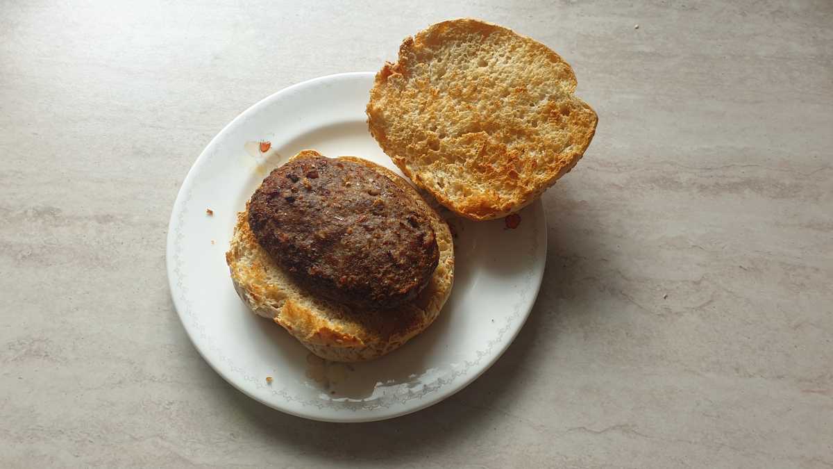 A view of a burger and bun cooked by the Sharp Dual Drawer 8l Digital Air Fryer with Sync Finish on a plate.