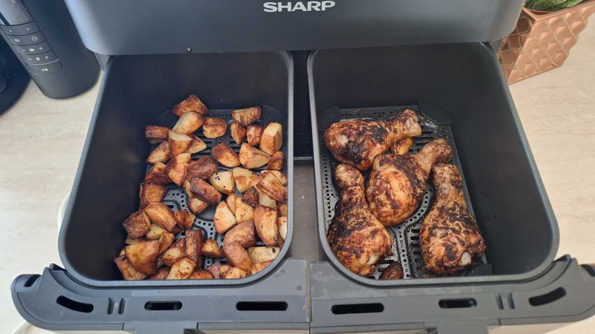 A view of potatoes and chicken legs cooked in two separate drawers in the Sharp Dual Drawer 8l Digital Air Fryer with Sync Finish