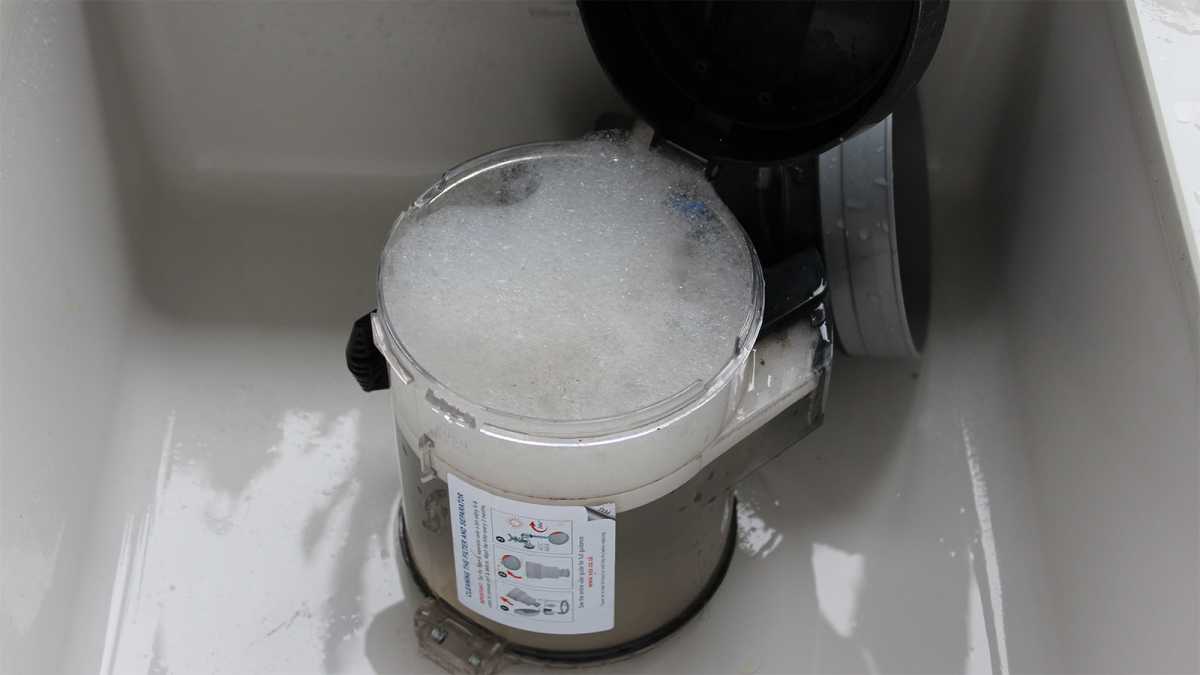 Vacuum cleaner container in a sink, filled with soapy water