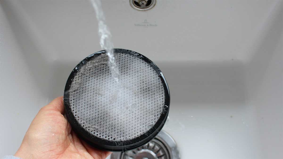 A vacuum filter washed under a tap