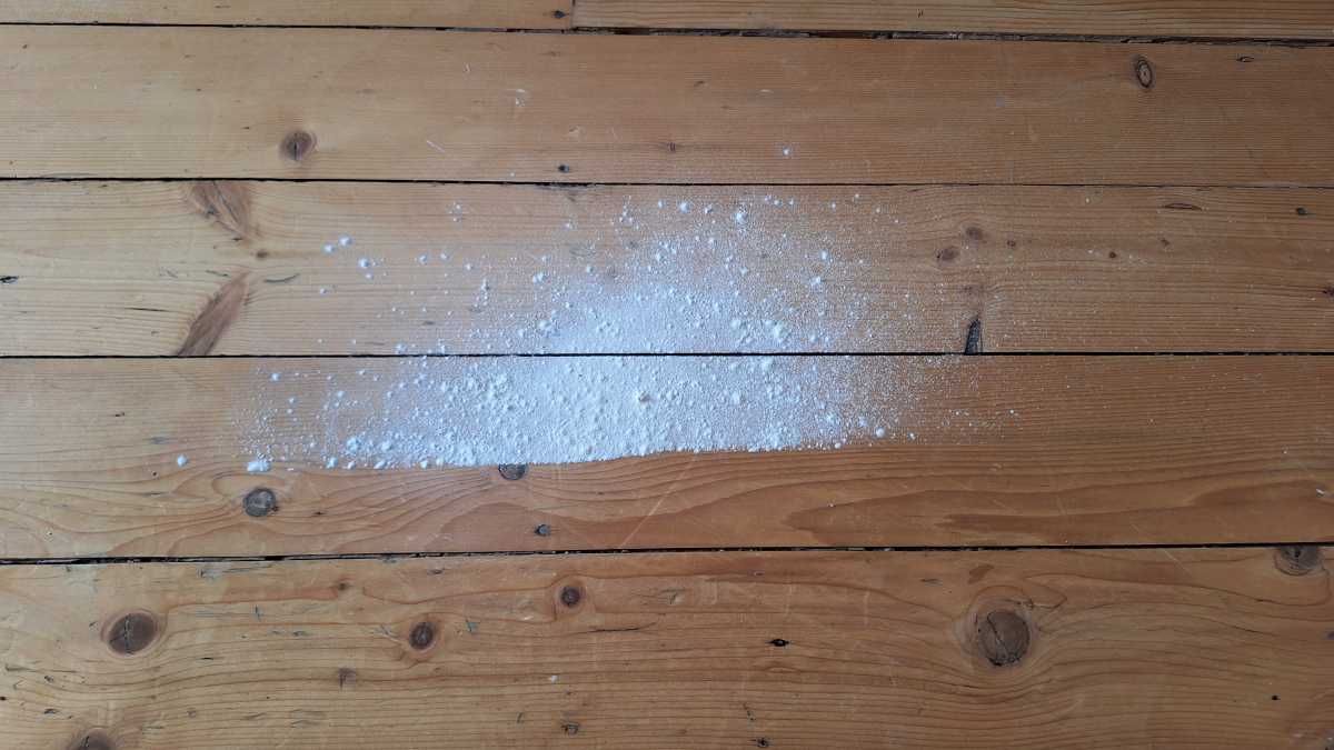 A hardwood floor showing the Tineco iFloor 5 Floor Washer flour test a quarter way through.  