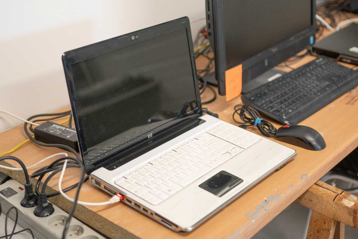 Old laptop next to old PC on wooden desk somewhere in Europe