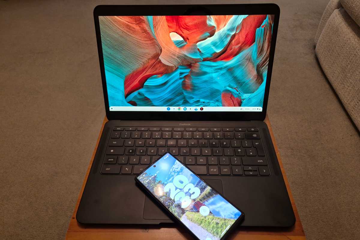 Computadora portátil Chromebook en un escritorio con bandeja de madera y teléfono Android en el teclado