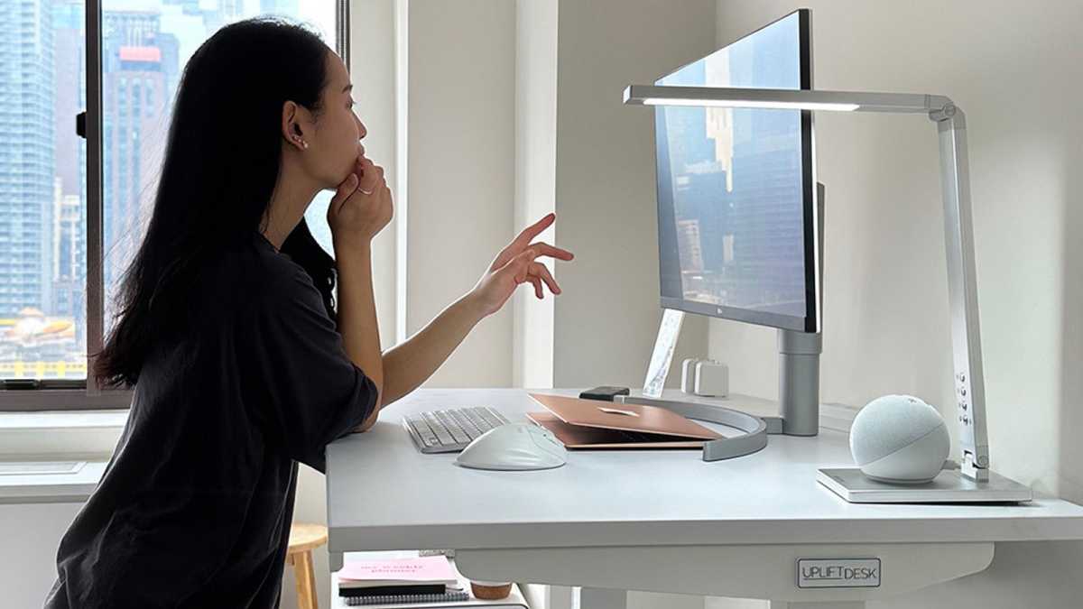 Woman using a desktop computer on a white standing desk