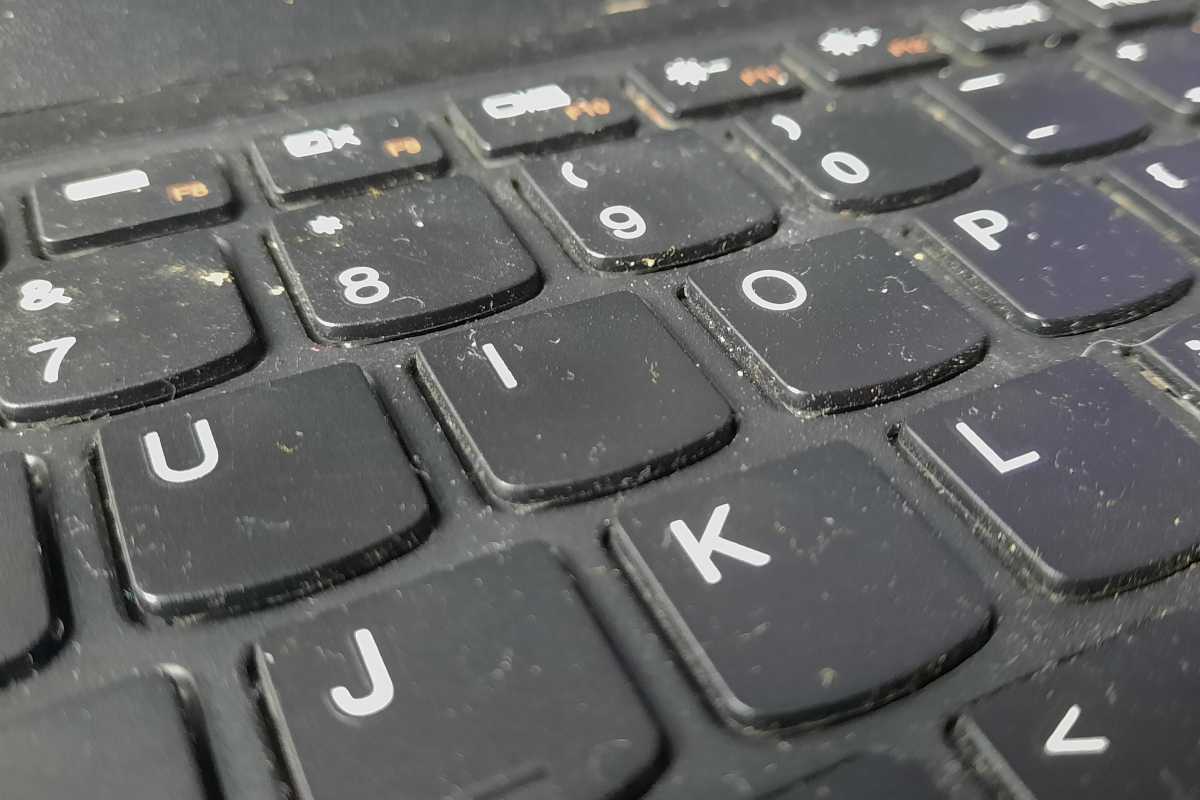 Dirty laptop keyboard covered in dust and grime closeup