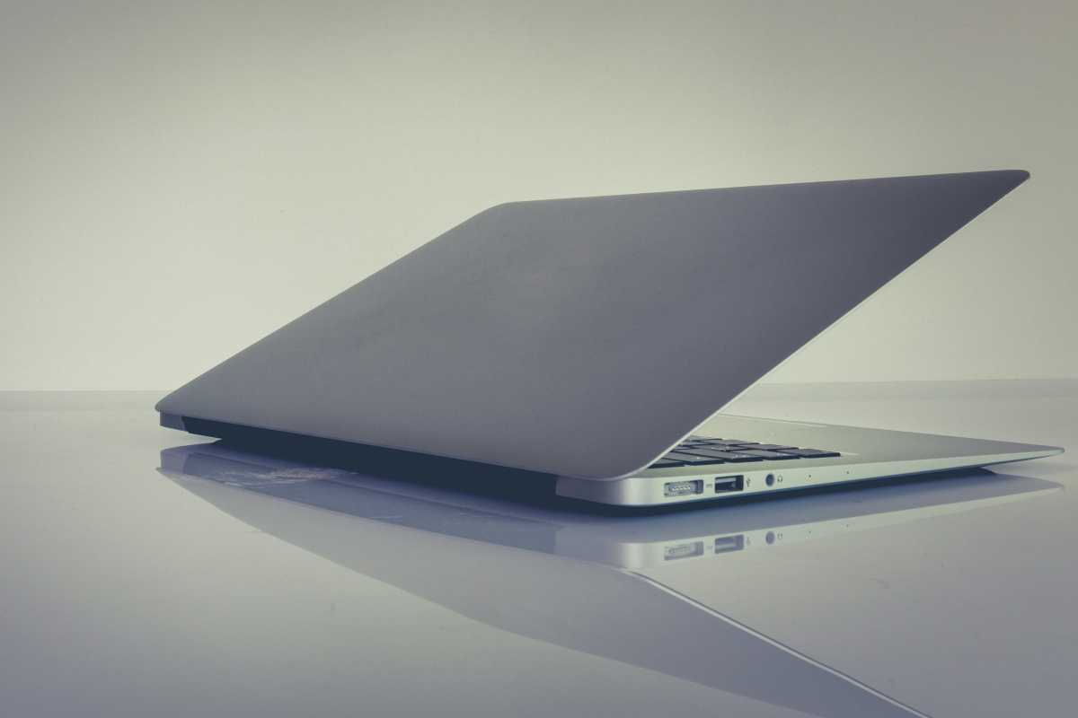 Half-closed notebook laptop on sleek surface and background