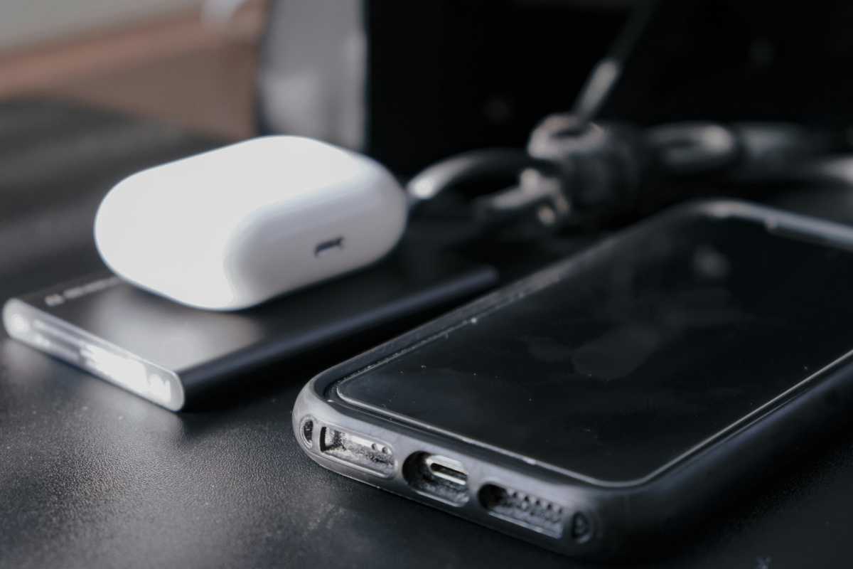 Phone next to portable storage drive on table with wireless earbuds case