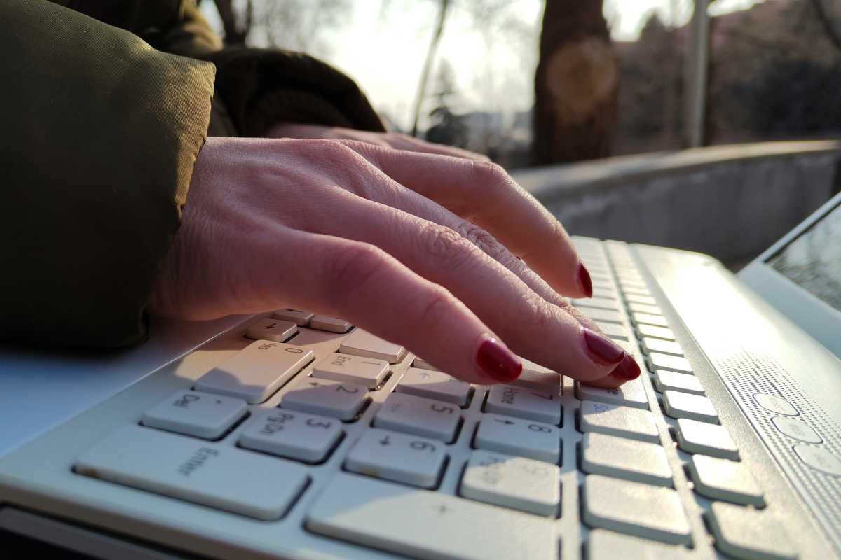 Woman hand with red nails using white laptop closeup