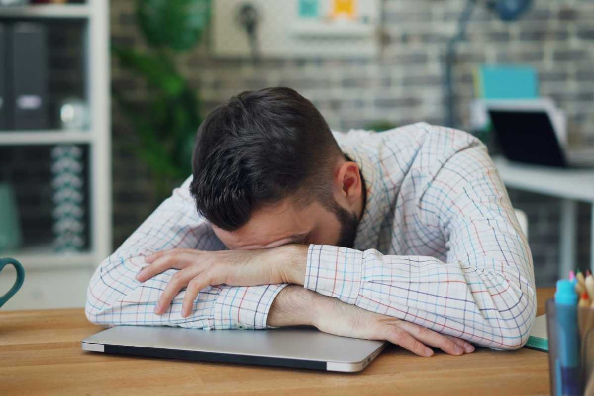 Office desk worker sleeping on top of his laptop on his workspace